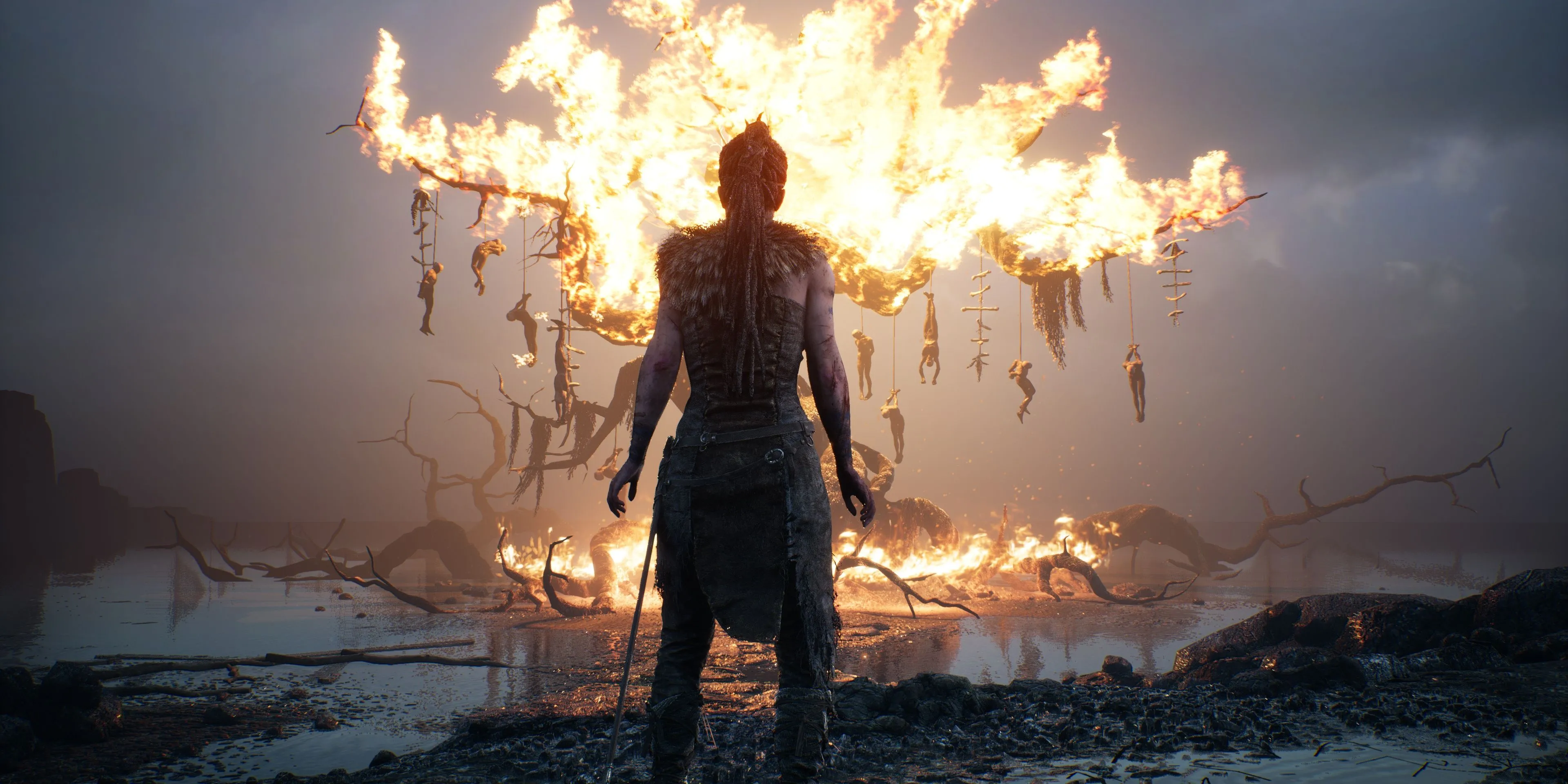 Senua đứng trước cây cháy rực trong Hellblade: Senua's Sacrifice thể hiện sự đối mặt với nội tâm
